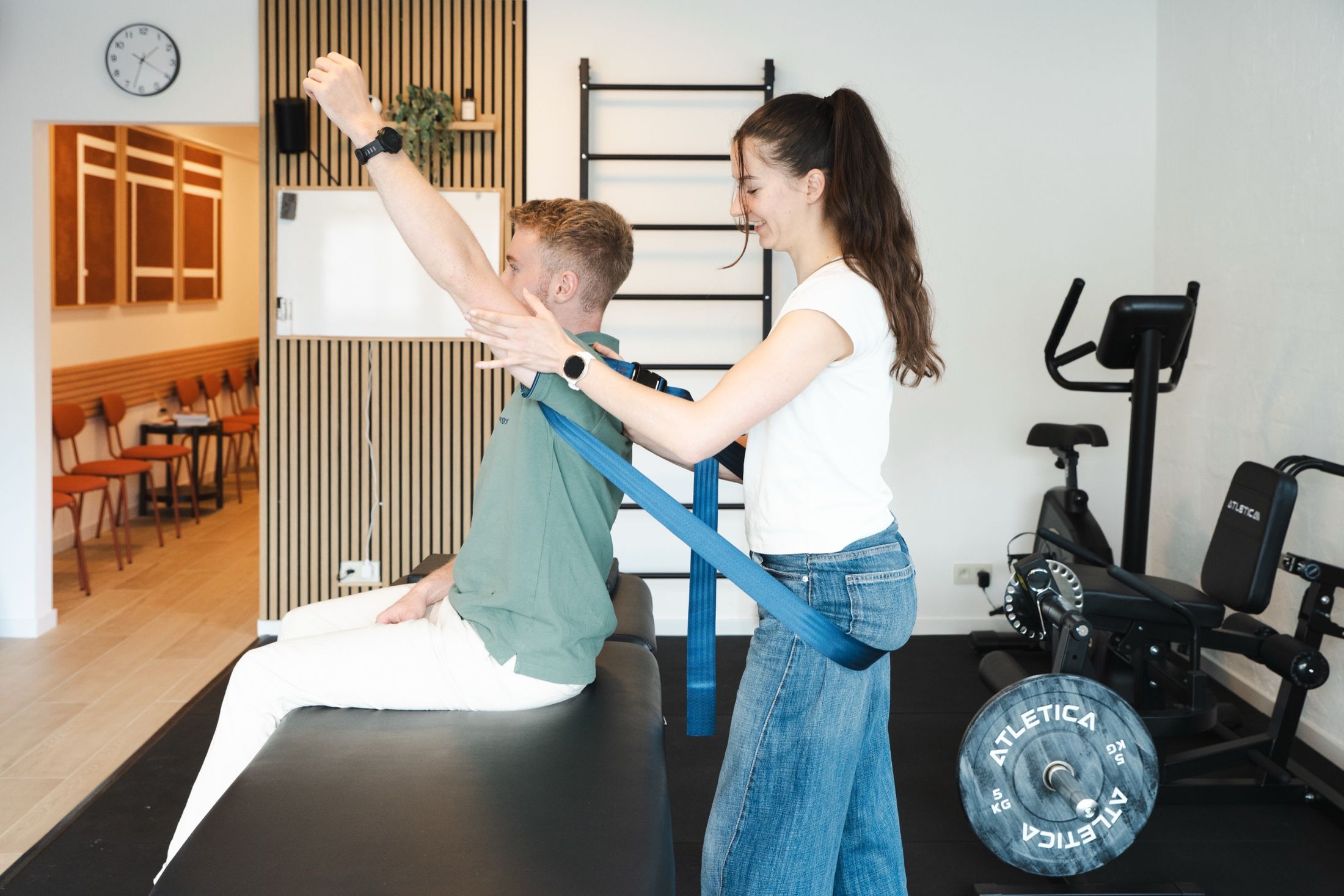 La salle de rééducation du centre pendant un exercice d'épaule encadré par une kinésithérapeute